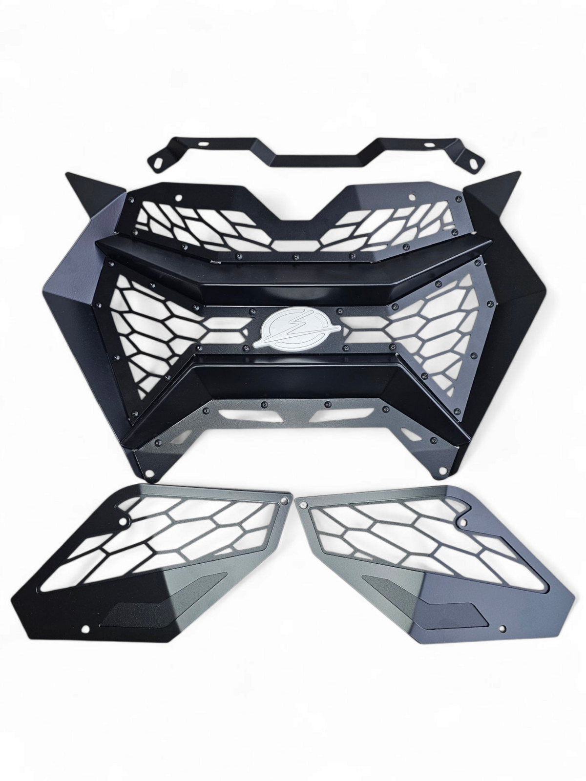 Volt 3-Piece Grille unboxed beside 2024 Can-Am Maverick R showing three grille
    sections, billet badge, and complete bolt-in hardware kit