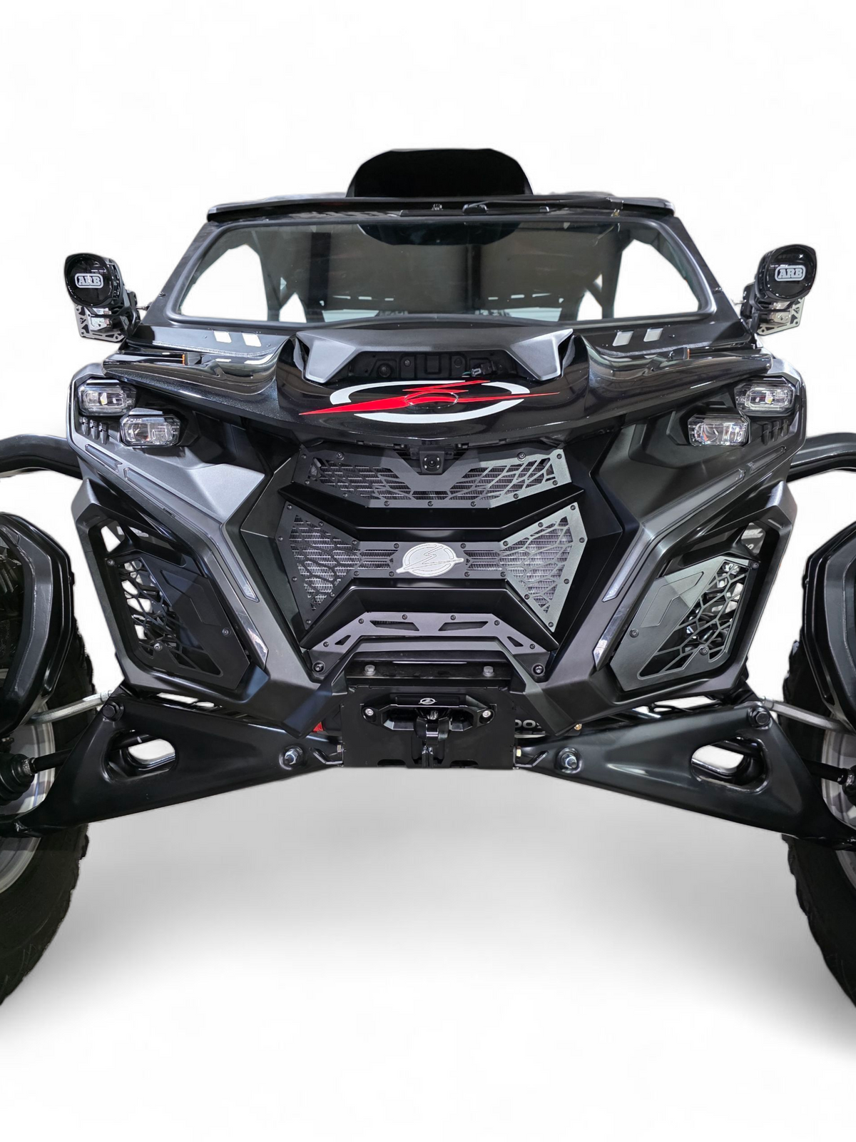 2024 Can-Am Maverick R fitted with Volt 3-Piece Grille in hammer black powder coat
    finish, full front view on a desert trail showing contour-matched fitment and
    billet aluminum badge detail